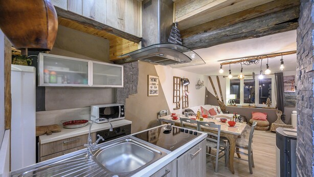 A modern kitchen with a central island, stainless steel appliances, and a rustic wooden ceiling.