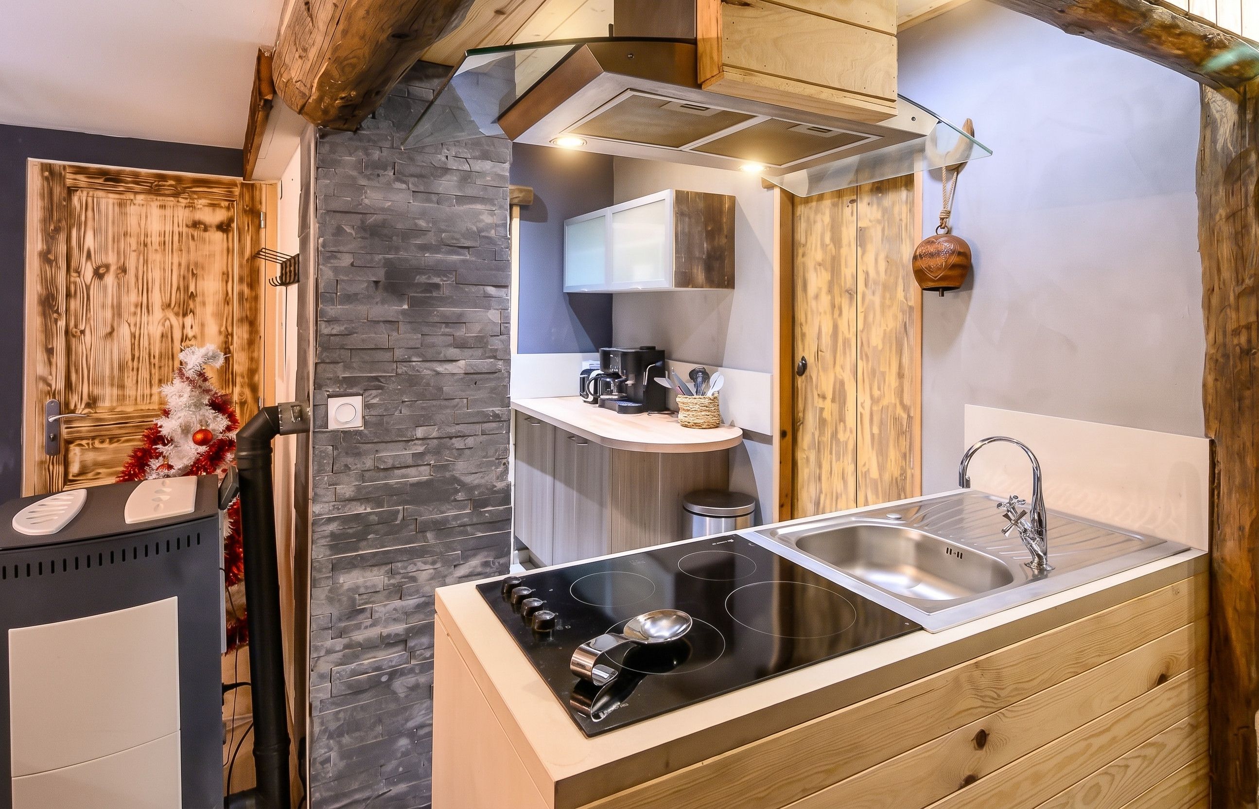 A modern kitchen with a stone wall, wooden cabinets, and a stainless steel sink.