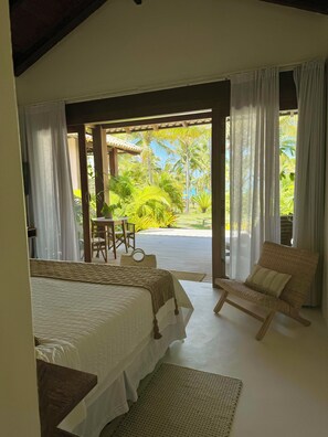 Un dormitorio con una cama, una silla, una mesa y vistas a un jardín.