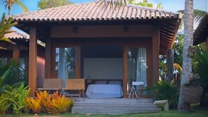 A two-story building with a tiled roof, a balcony with wicker furniture, and a bed visible inside. - Vila Bela Vista Corumbau (Prado)