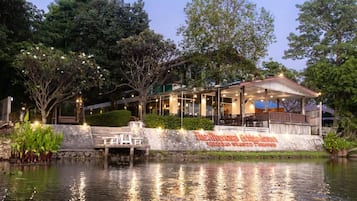 A riverside restaurant with outdoor seating and a stone wall with signage.