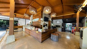 Un intérieur en bois avec un comptoir d’accueil, des luminaires suspendus et un téléviseur.