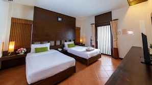 Une chambre d’hôtel avec deux lits, un bureau, un téléphone, une lampe et une fenêtre avec des rideaux.