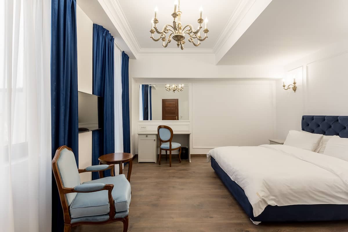 Ein Hotelzimmer mit Bett, Schreibtisch, Stuhl, kleinem Tisch und Spiegel.
