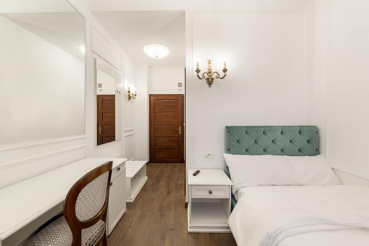 Ein Schlafzimmer mit Bett, Schreibtisch, Stuhl, Kleiderschrank und Spiegel.