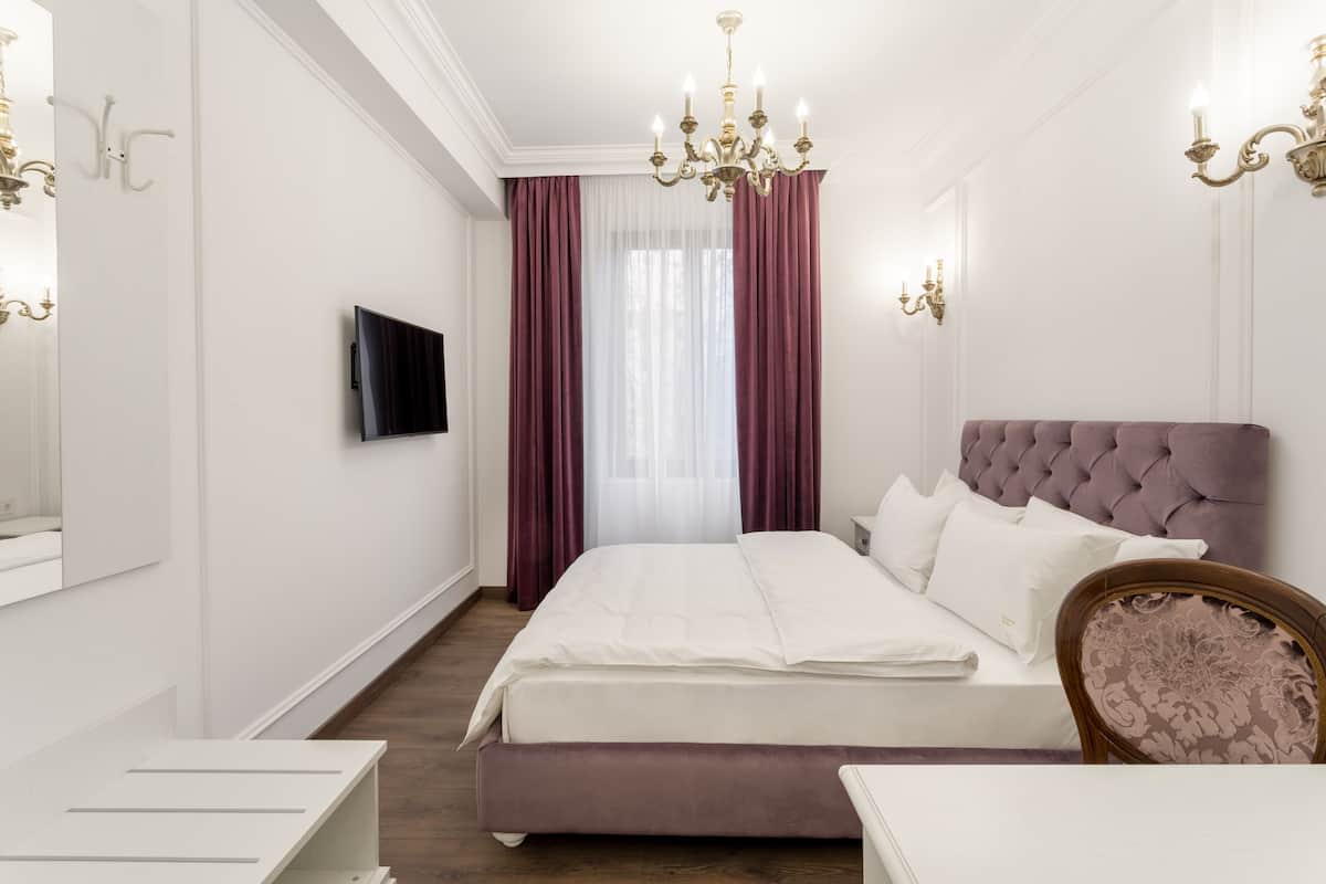Ein modernes Schlafzimmer mit einem großen Bett, einem Fernseher und einer Kristallleuchter.