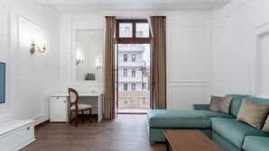 Un salon moderne avec un canapé vert, une table basse en bois, un bureau avec une chaise et un grand miroir.