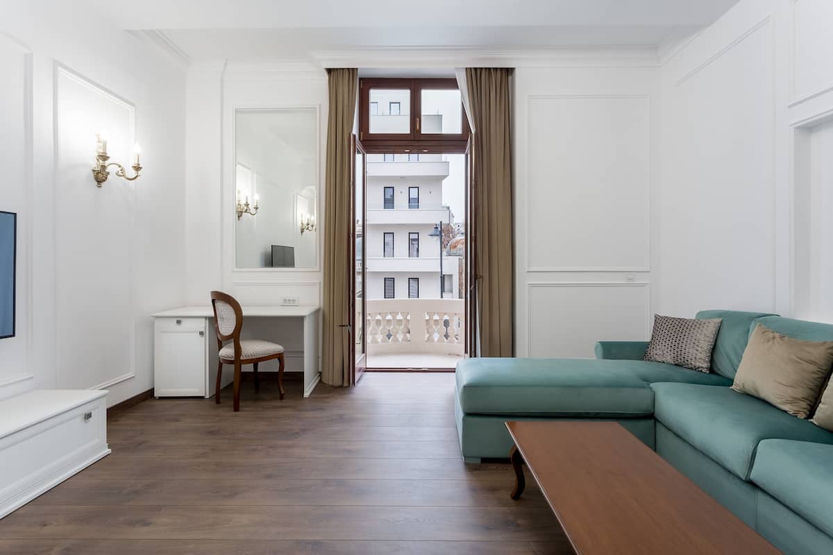 Ein modernes Wohnzimmer mit einem grünen Sofa, einem Holztisch, einem Schreibtisch mit Stuhl und einem großen Spiegel.