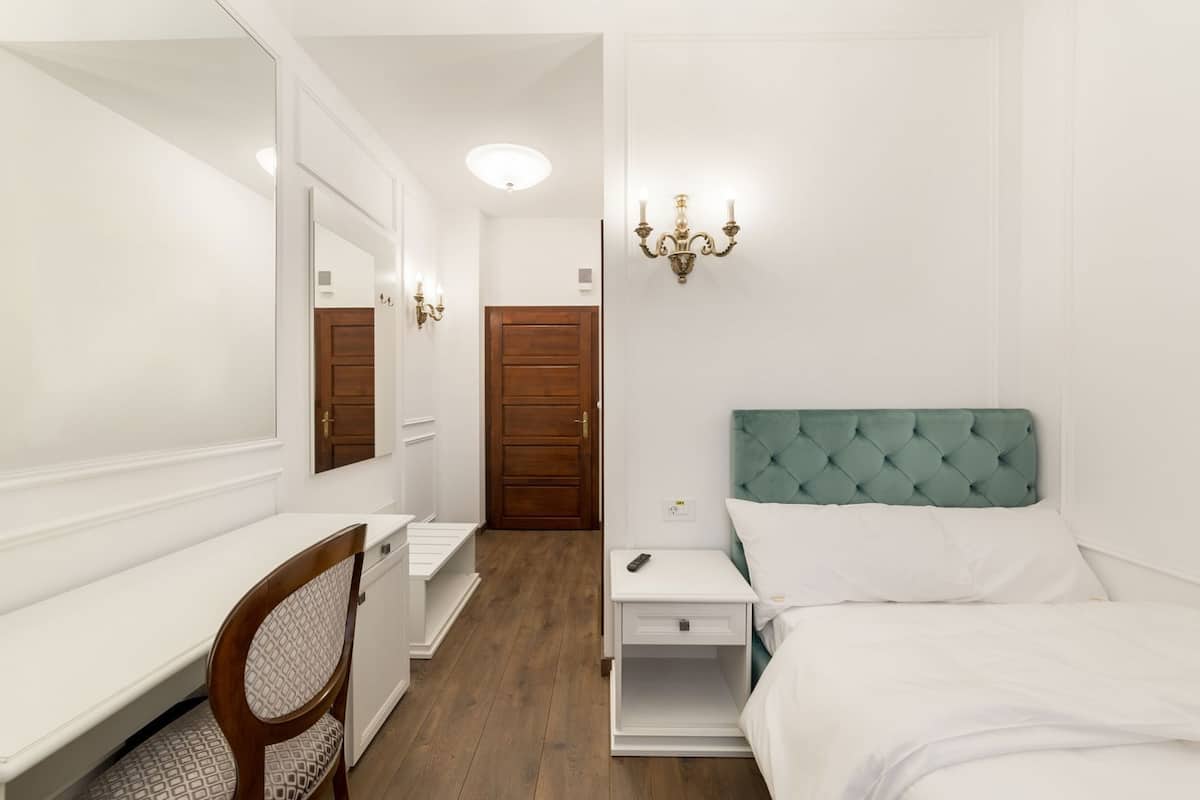 Ein Hotelzimmer mit Bett, Schreibtisch, Stuhl, Kleiderschrank und einer Tür.