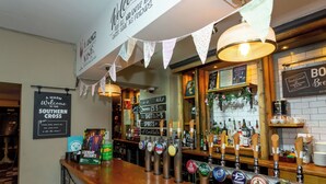 Un'area bar con diverse spine di birra, un cartello che recita “Benvenuti al Southern Cross” e una lavagna con il menu.