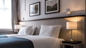 Una camera d'albergo con un letto grande, due comodini e due lampade a parete.