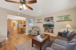 A living room with a sofa, a coffee table, a chair, a bookshelf, and a television.