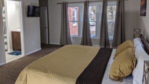 A bedroom with a large bed, a television on the wall, and a view of the outside through the window. - Lakeview Five Bedrooms Cape Cod Near Quantico and Historic Fredericksburg (Stafford Courthouse)