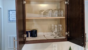 A kitchen with a wooden cabinet containing glassware and a metal dish rack on the countertop. - Lakeview Five Bedrooms Cape Cod Near Quantico and Historic Fredericksburg (Stafford Courthouse)