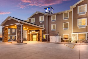 A hotel with a covered entrance, stone pillars, and a sign indicating it is a Cobblestone Hotel & Suites. - Cobblestone Hotel & Suites - Cozad (Cozad)
