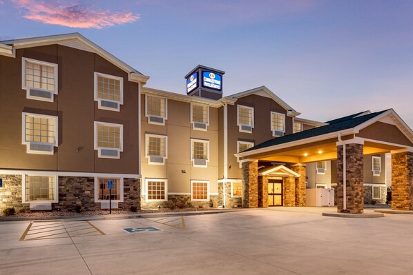 A hotel with a stone facade, multiple windows, and a sign indicating it is a Holiday Inn Express. - Cobblestone Hotel & Suites - Cozad (Cozad)