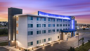 Un hotel moderno con tejado plano, numerosas ventanas y una entrada iluminada en azul.
