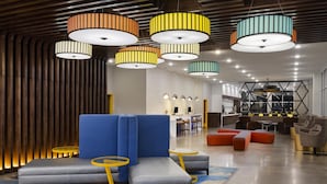 Un vestíbulo moderno con un sofá modular, mesas redondas e iluminación colgante de colores.