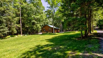 A cabin surrounded by a lush green landscape with a clear sky.