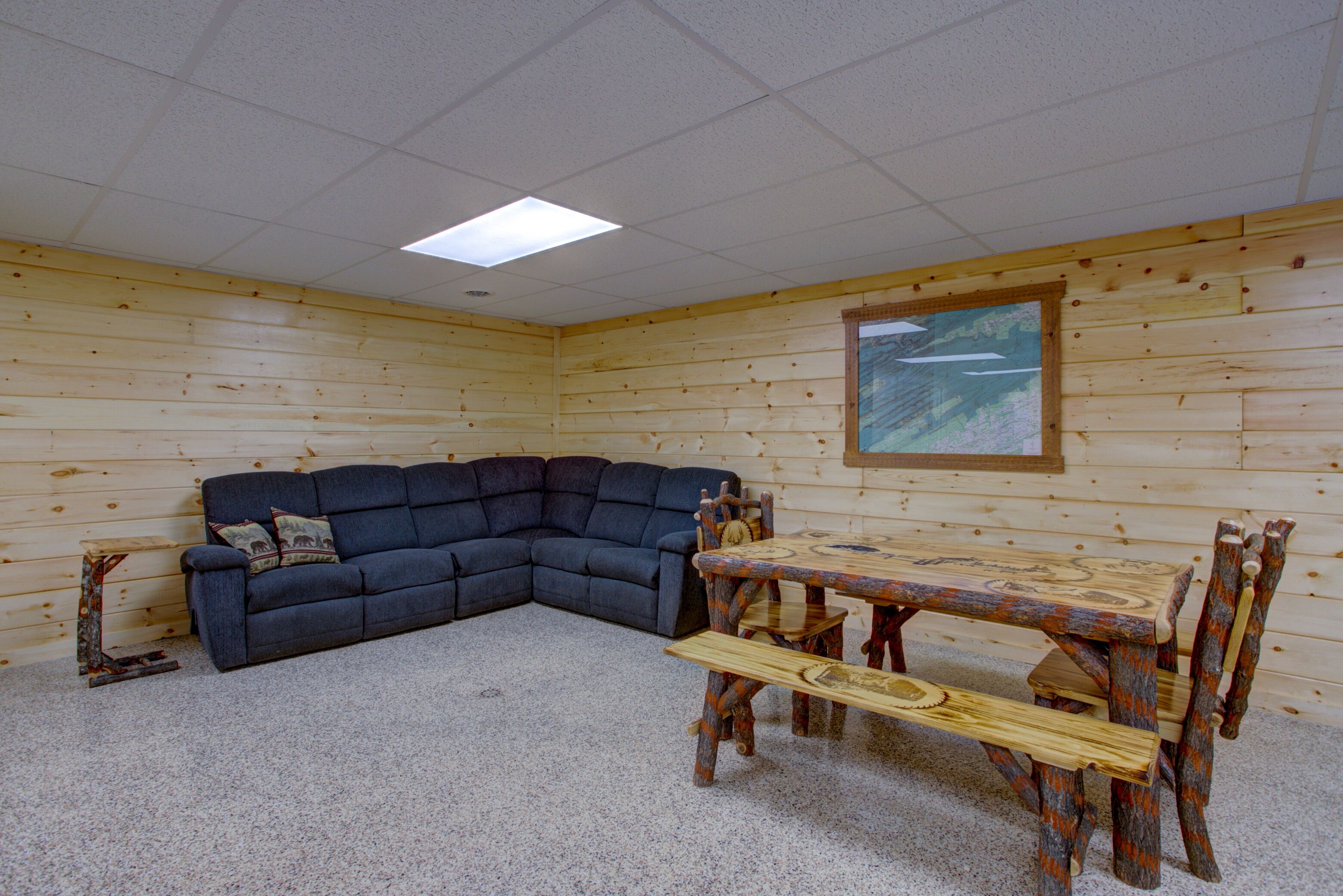 Une pièce comprenant un canapé d’angle, une table à manger en bois avec des bancs, et un tableau accroché au mur.