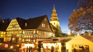 A traditional half-timbered building with a clock tower, surrounded by market stalls and a tented area. - Eversberg1 - Apartment/ Assembly Meschede-Eversberg (Meschede)
