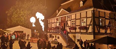 A traditional building with a staircase leading to a balcony, surrounded by a cobblestone square.