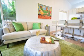 Una sala de estar moderna con un sofá, una mesa redonda con comida y un área de cocina con sillas.