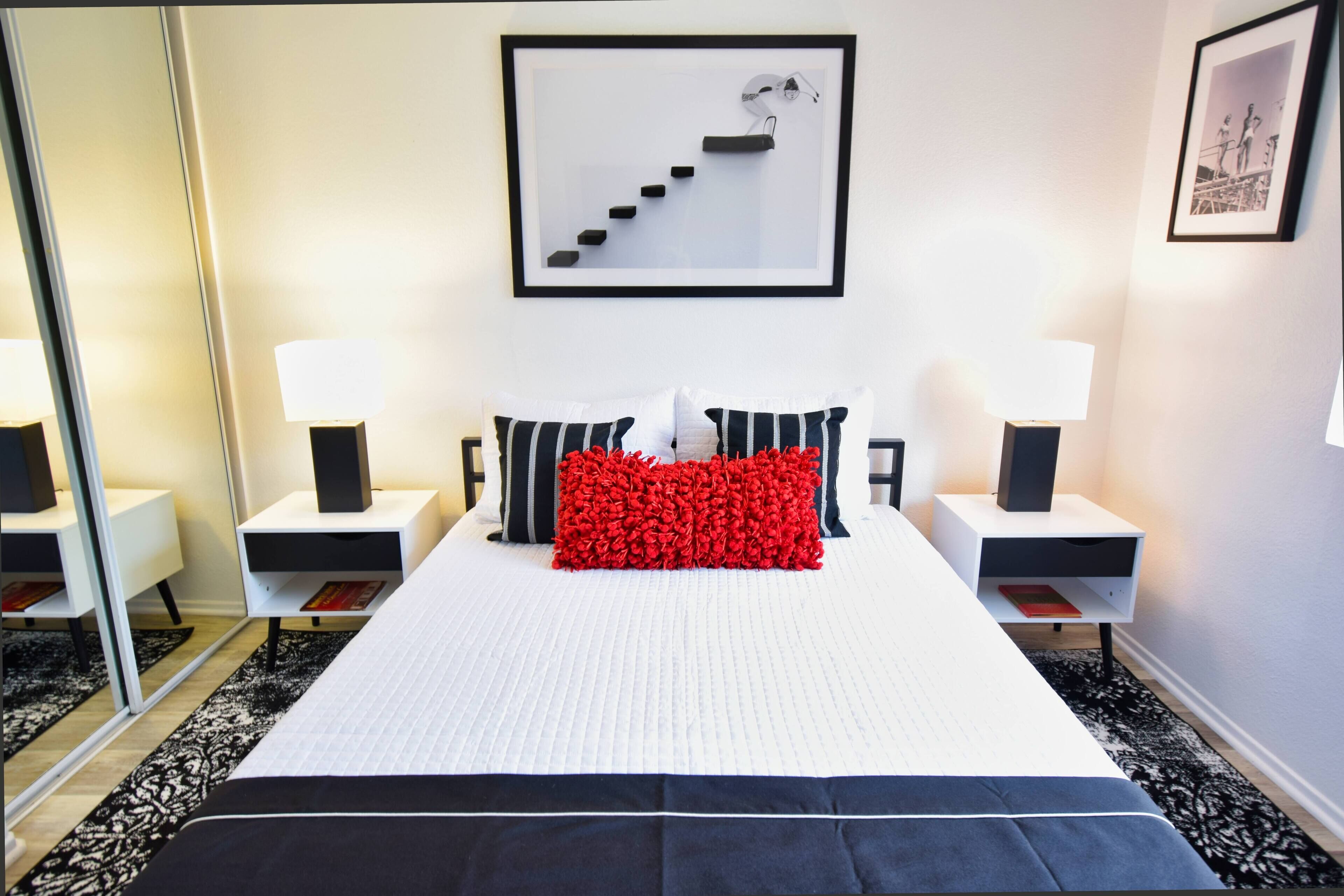 A neatly arranged bedroom with a large bed, two bedside tables, and a framed picture on the wall.