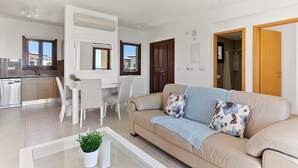 Ett modernt vardagsrum med en beige soffa, ett soffbord och en matplats med stolar och ett bord.