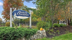 A sign for Beach Dreams Cottage with a stone wall and autumn foliage. - Cute and Comfy Cottage - 1 Mile to Wells Beach & 3 Miles to Ogunquit Beach! (Wells)