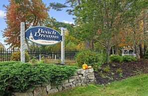 Welcome to Beach Dreams Cottages, nestled among a beautifully maintained garden with a stone wall and lush greenery.