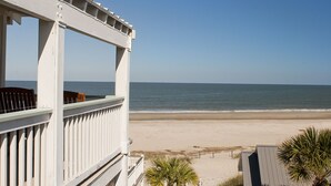 A balcony with a view of the beach and ocean.