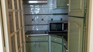 A compact kitchen with green cabinets, a microwave, and a stainless steel range hood. - Nice air-conditioned studio - wifi - sea view and direct beach access (Palavas-les-Flots)