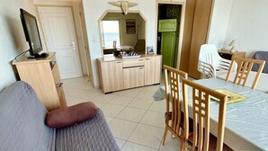 A hotel room with a bed, a desk, a chair, a television, and a green door. - Nice air-conditioned studio - wifi - sea view and direct beach access (Palavas-les-Flots)