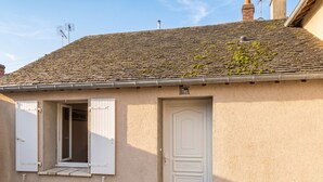 A building with a tiled roof, a white door, and a window with shutters. - Homerez - Studio with parking in Montargis (Montargis)