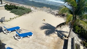 Un espace aménagé au bord de la piscine, avec des chaises longues et une vue sur la plage.