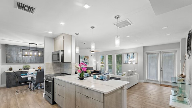 A modern kitchen with a central island, a dining area, and a living space with a sofa and a coffee table.