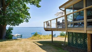 Une terrasse en bois avec des sièges extérieurs donnant sur une étendue d’eau.