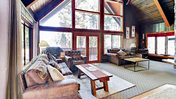 A spacious living room with a high ceiling, large windows, and a cozy fireplace.