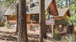 A cabin with a large front porch, multiple windows, and a chimney.