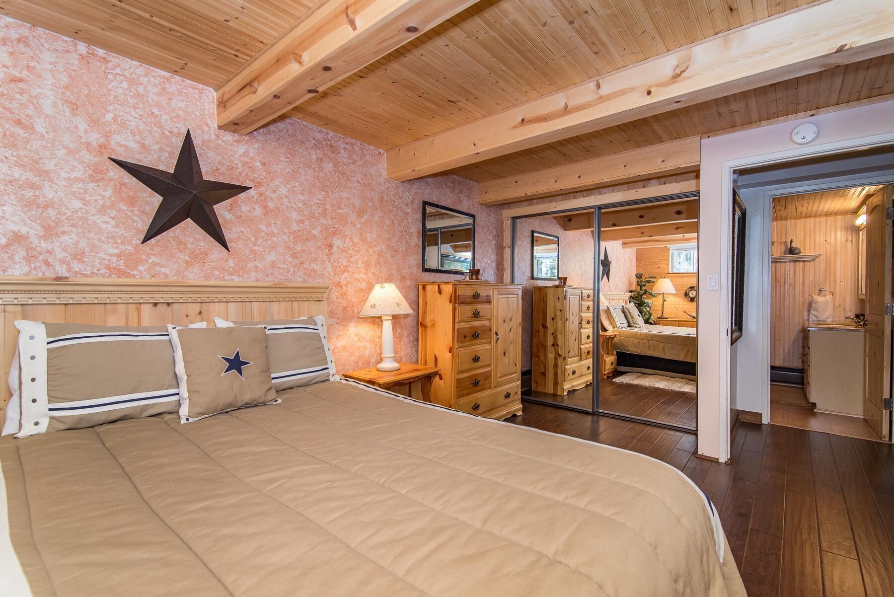 Un dormitorio con una cama grande, cabecera de madera, un adorno de estrella en la pared y un armario de madera.