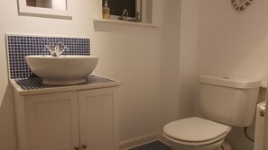 A bathroom with a white sink, blue-tiled backsplash, and a white toilet.