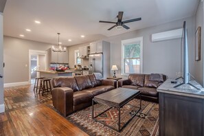 A modern living room with a brown leather sofa, a wooden coffee table, and a TV on a stand. - Atchee House I: Grill, Bikes & Fire Pit (Fruita)