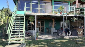 Een tweelaags huis met een balkon, een trap en een veranda met buitenmeubels.