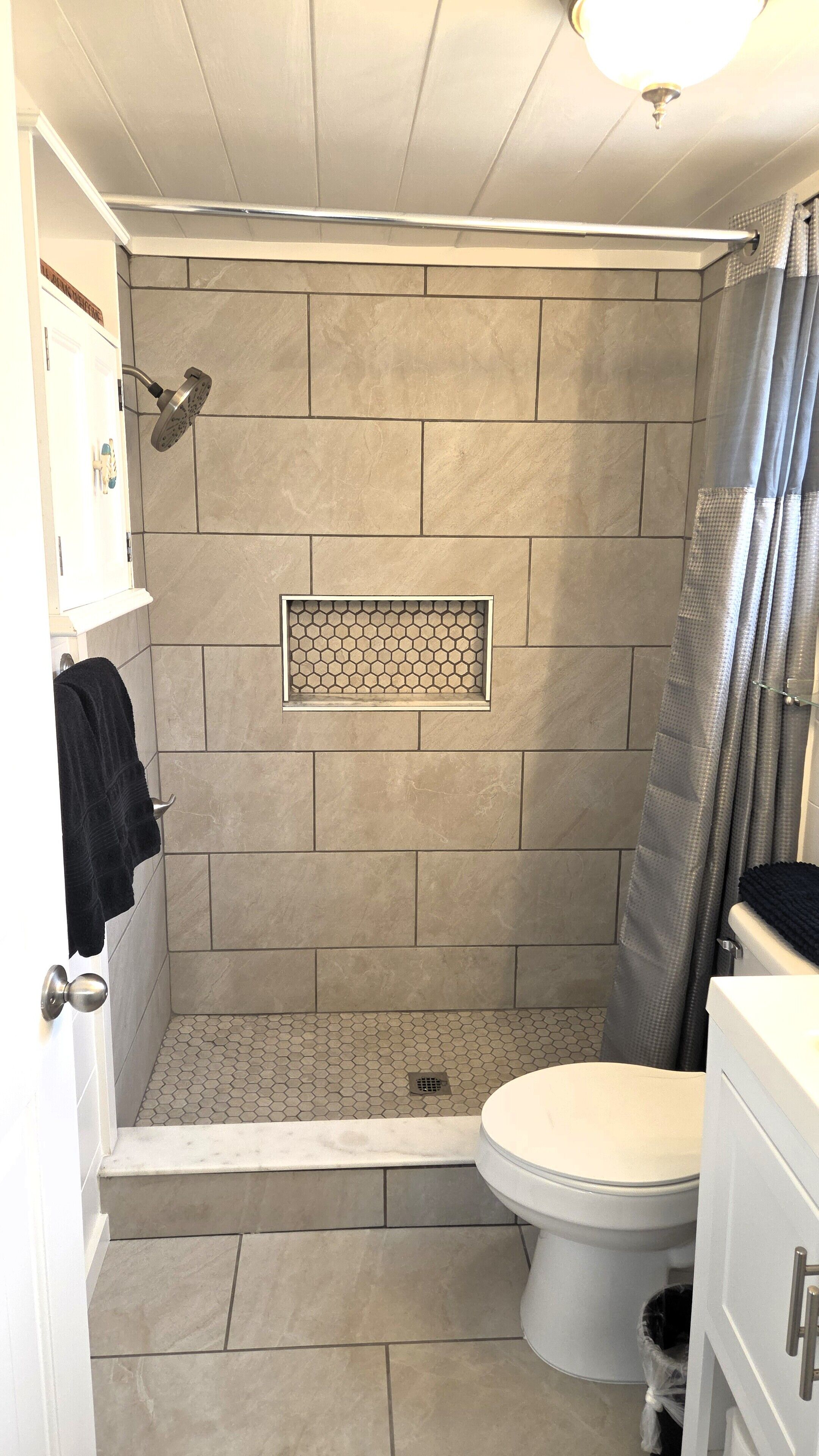 Een badkamer met een douche, toilet en wastafel.