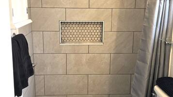 Een badkamer met een douche, toilet en wastafel.