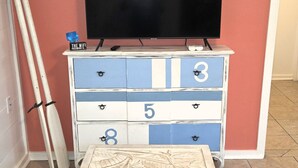 Habitació amb un televisor sobre un taulell, una petarrera i un sofà.
