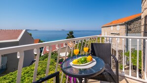 Un balcon avec une table préparée pour le petit-déjeuner, offrant une vue sur la côte.