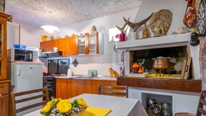 Une cuisine avec des meubles de rangement en bois, un four à micro-ondes et une table à manger agrémentée d’un set de table jaune et d’un vase de fleurs.