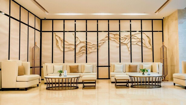 A modern interior with three sofas and two round tables, a decorative wall with abstract patterns, and a floor with a light-colored finish. - Days Inn by Wyndham Business Place Sichuan Bazhong (Bazhong)